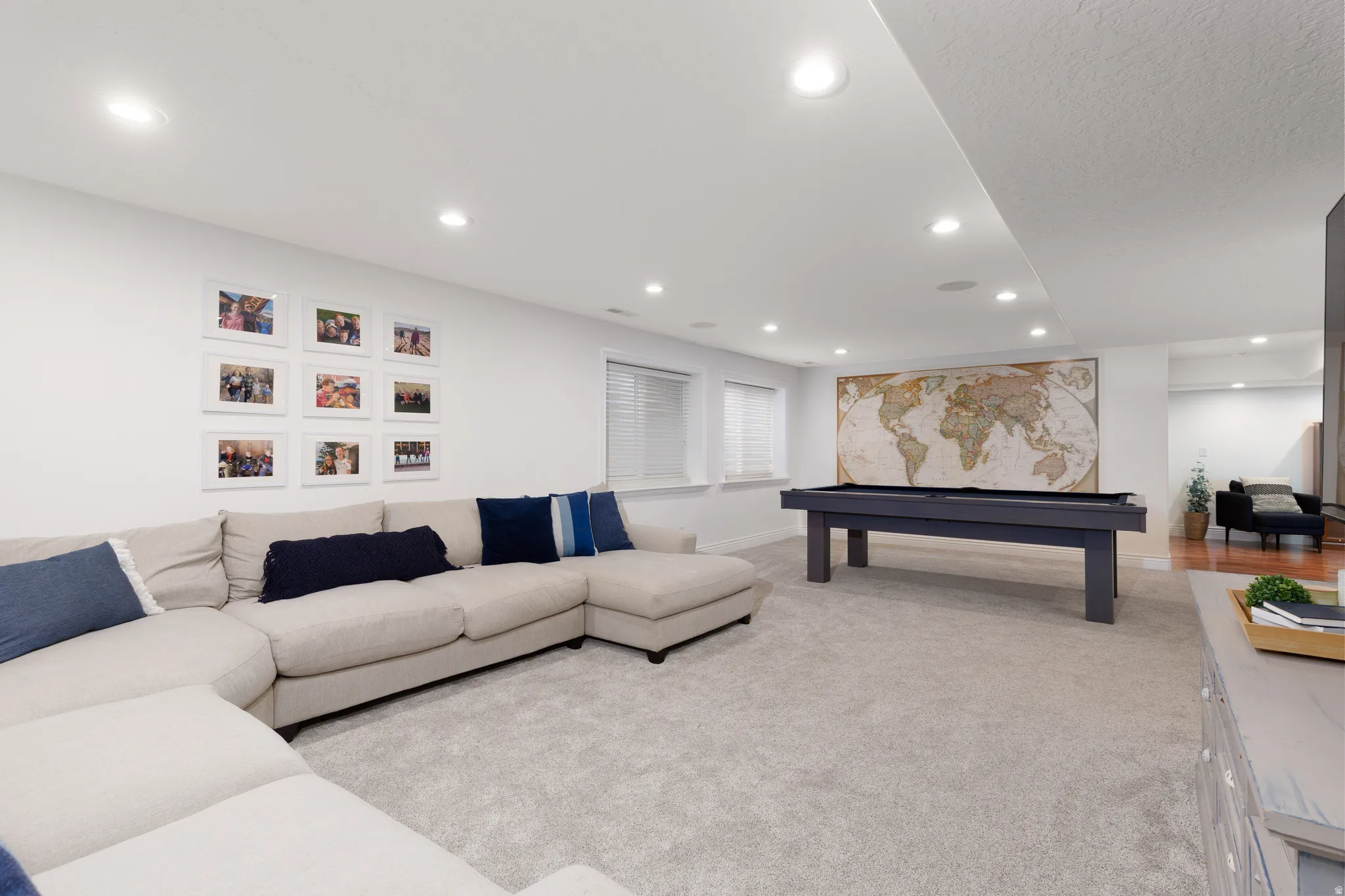 Spacious recreation room featuring recessed lighting, light-toned carpeting, white walls, and multiple windows