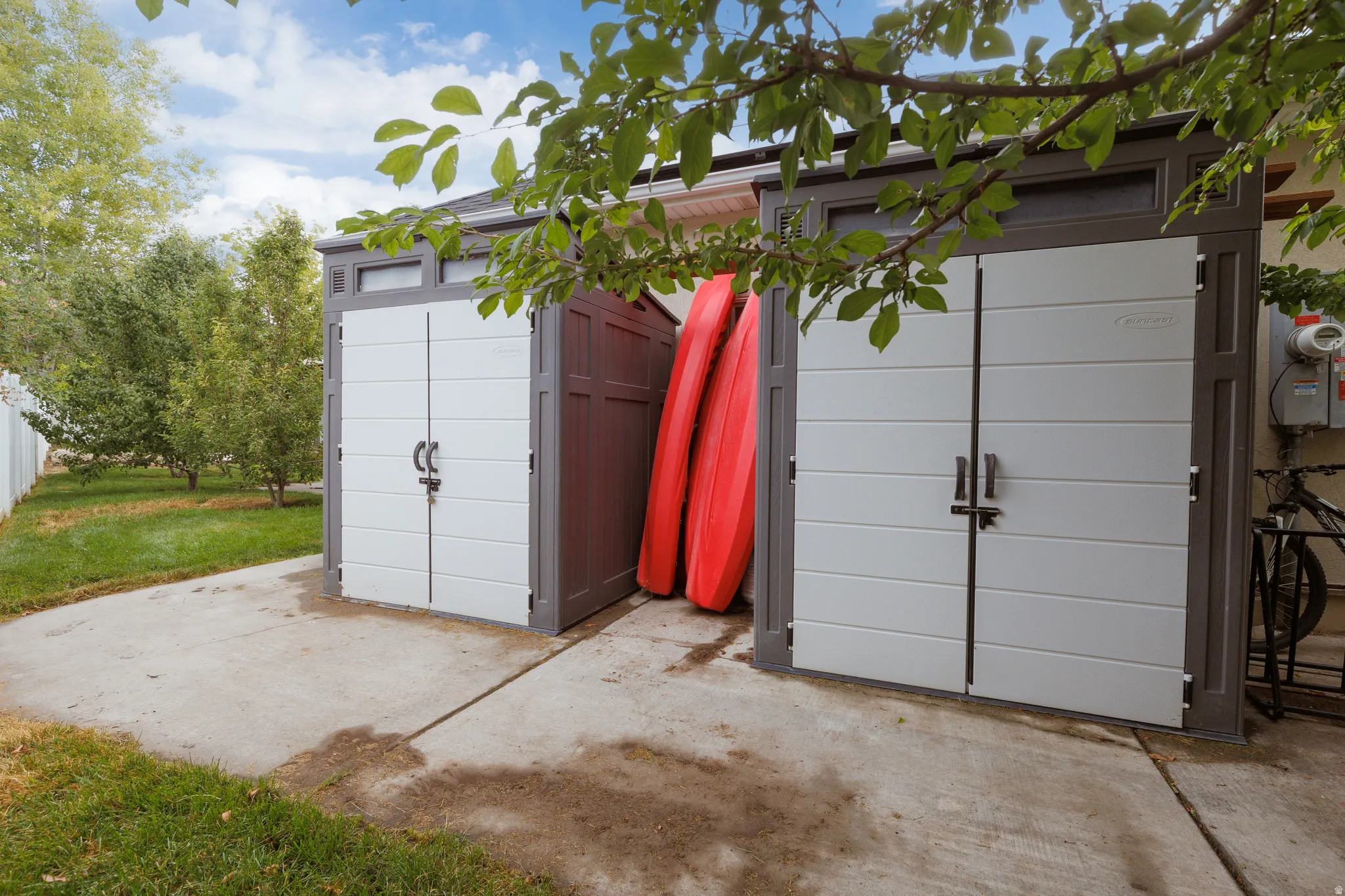 Two contemporary storage sheds with double doors, gray frames, and white paneling