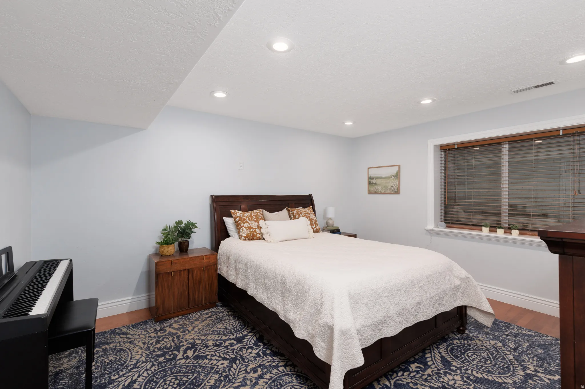 Bedroom featuring recessed lighting, light blue wall paint, wood-finish flooring, a window with wood blinds, and white baseboards