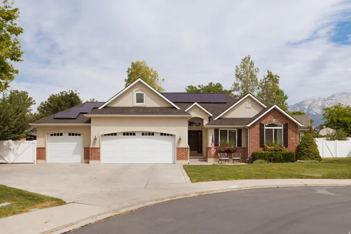 Stucco and brick facade residence featuring dark roofing and integrated solar panels