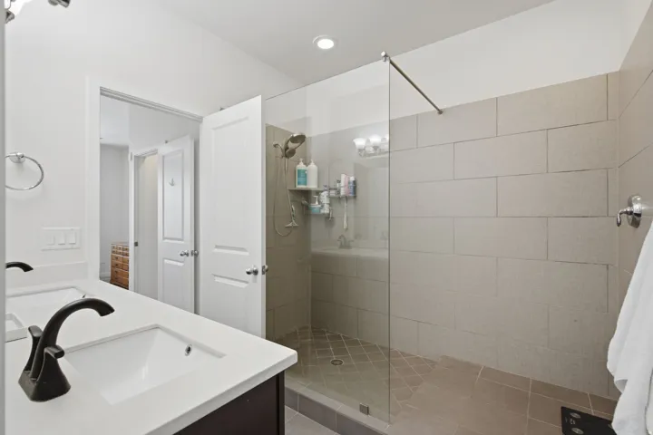 Spacious bathroom featuring a frameless glass shower enclosure with floor-to-ceiling tiling