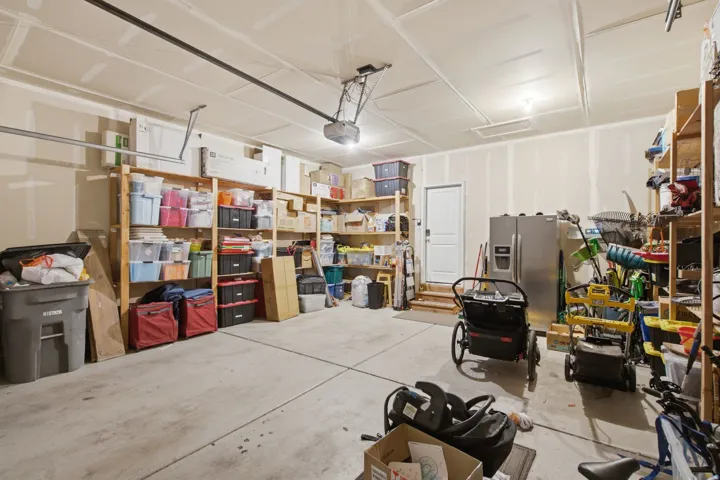 Spacious garage featuring concrete flooring, an attached garage door opener, and overhead lighting