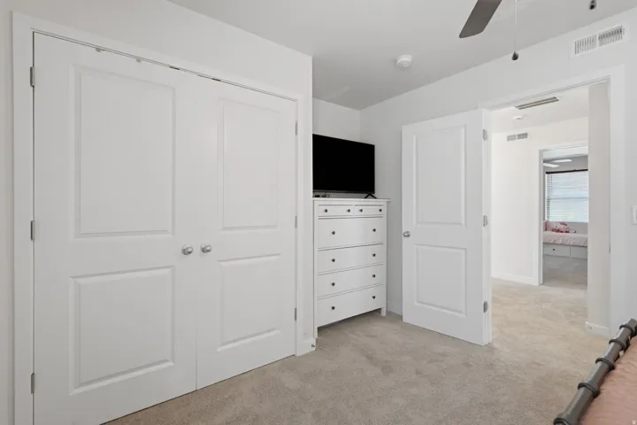 Carpeted interior space featuring white paneled bi-fold closet doors with polished hardware