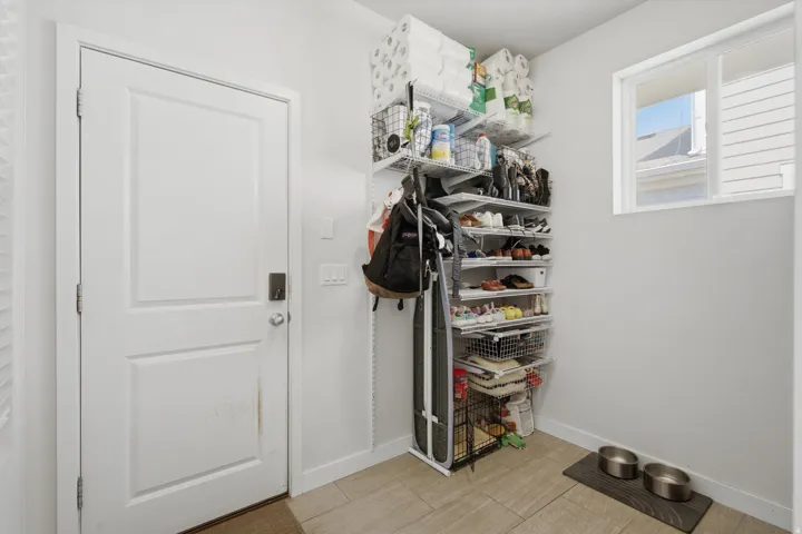 Built-in wire shelving system, light-toned tile flooring, white interior door, and a sliding window with natural light