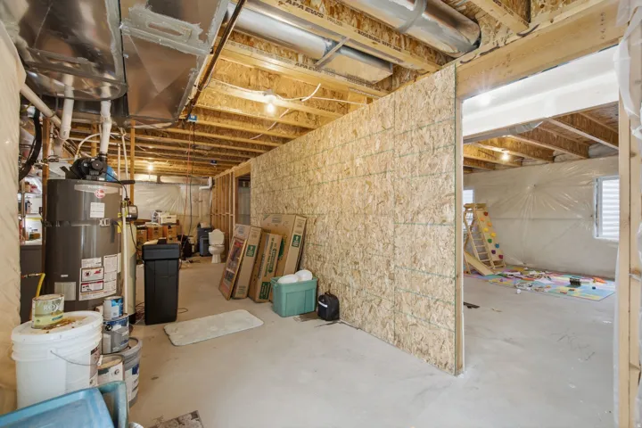 Partially finished basement featuring exposed ceiling joists, concrete flooring, and a framed room partition