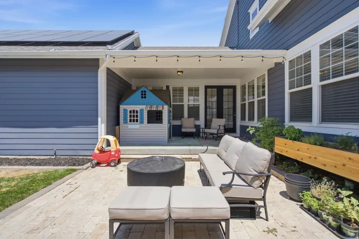 Expansive paver patio with a covered porch featuring string lighting