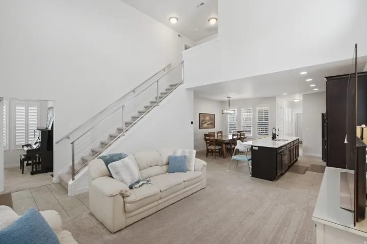 Two-story living area featuring a contemporary cable railing staircase, recessed lighting, and neutral carpeting