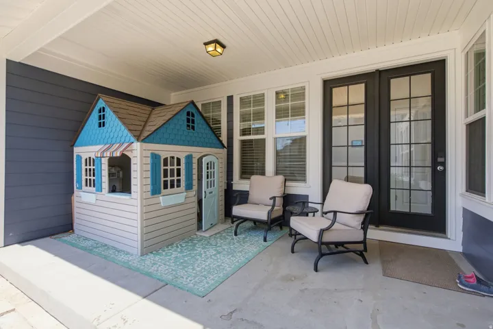 Covered porch featuring concrete flooring, a beadboard ceiling, dark siding, and white trim