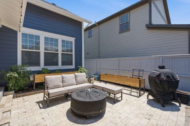 Paver patio area featuring a privacy fence, raised planter boxes, and exterior siding