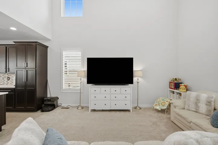 Spacious open-concept living area featuring a high vaulted ceiling, upper transom window, and neutral wall tones