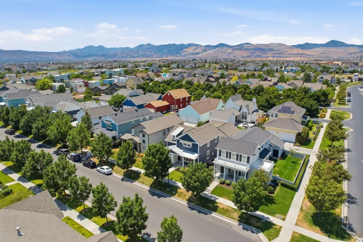 Expansive residential neighborhood featuring diverse architectural styles, tree-lined streets, and distant mountain ranges