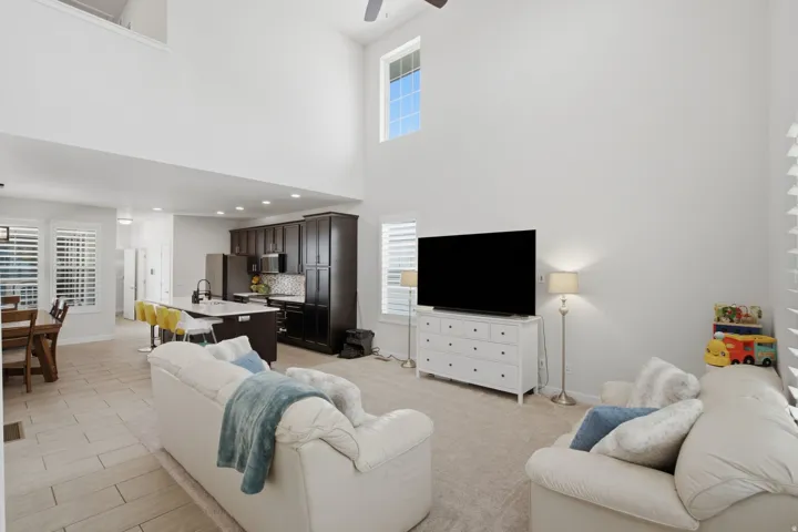 Vaulted living space featuring an upper-level window and neutral carpeting
