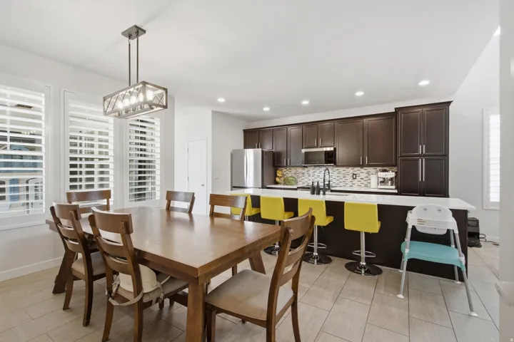 Open-concept kitchen and dining area featuring dark wood-finish cabinetry, a large kitchen island with a white countertop, and tile flooring