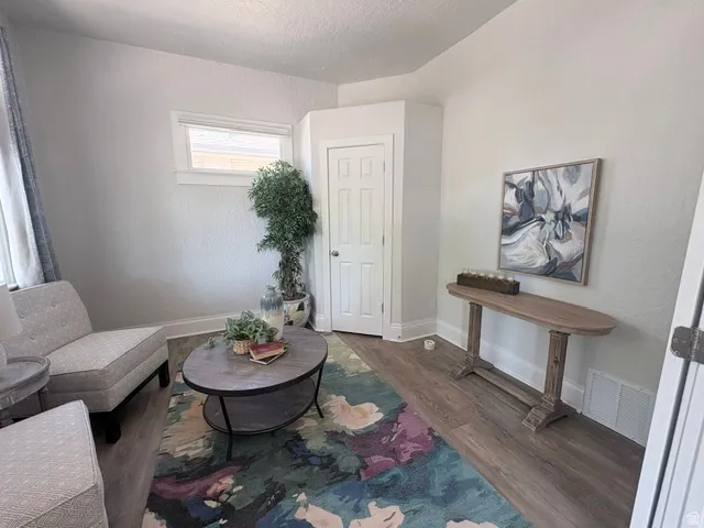 Light-filled interior space featuring wood-finish flooring, a white paneled door, and a horizontal window