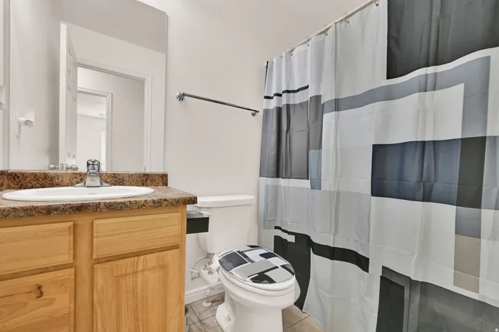 Bathroom featuring a single vanity with a laminate countertop, undermount sink, and chrome faucet