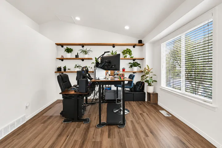 Vaulted ceiling with recessed lighting, large window with blinds, wood-finish flooring, and built-in wall shelving