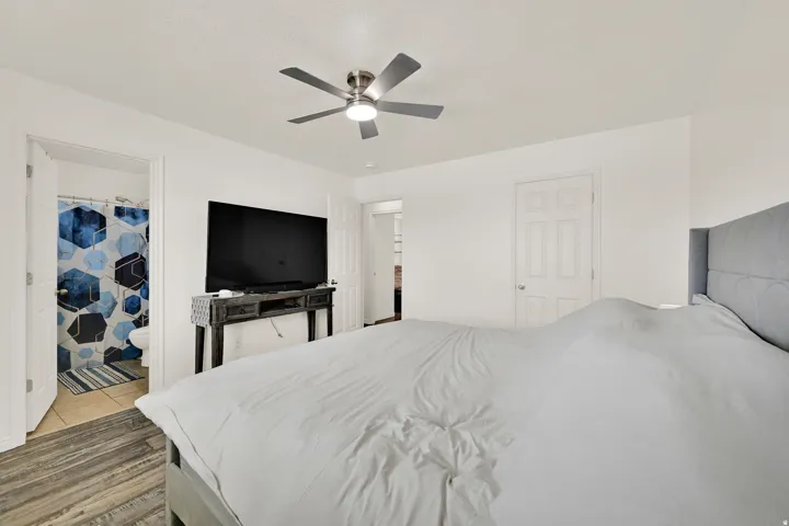 Bedroom featuring wood-finish flooring, a ceiling fan with integrated lighting, and white panel doors