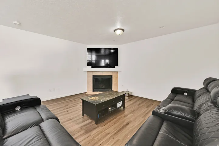 Living area featuring wood-finish flooring and a corner fireplace with a light-toned tile surround and white mantle