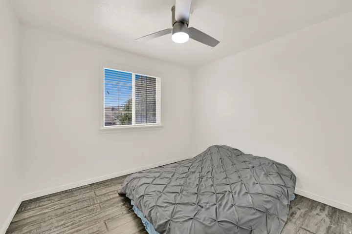 Room featuring light gray wood-finish flooring, white walls, and a window with horizontal blinds