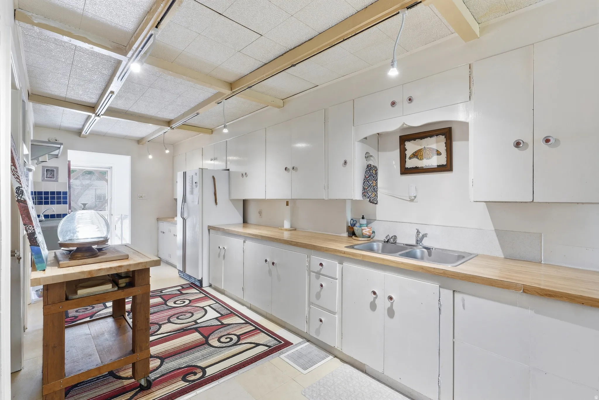 Full kitchen featuring extensive white cabinetry, light wood-finish countertops, and a double basin stainless steel sink