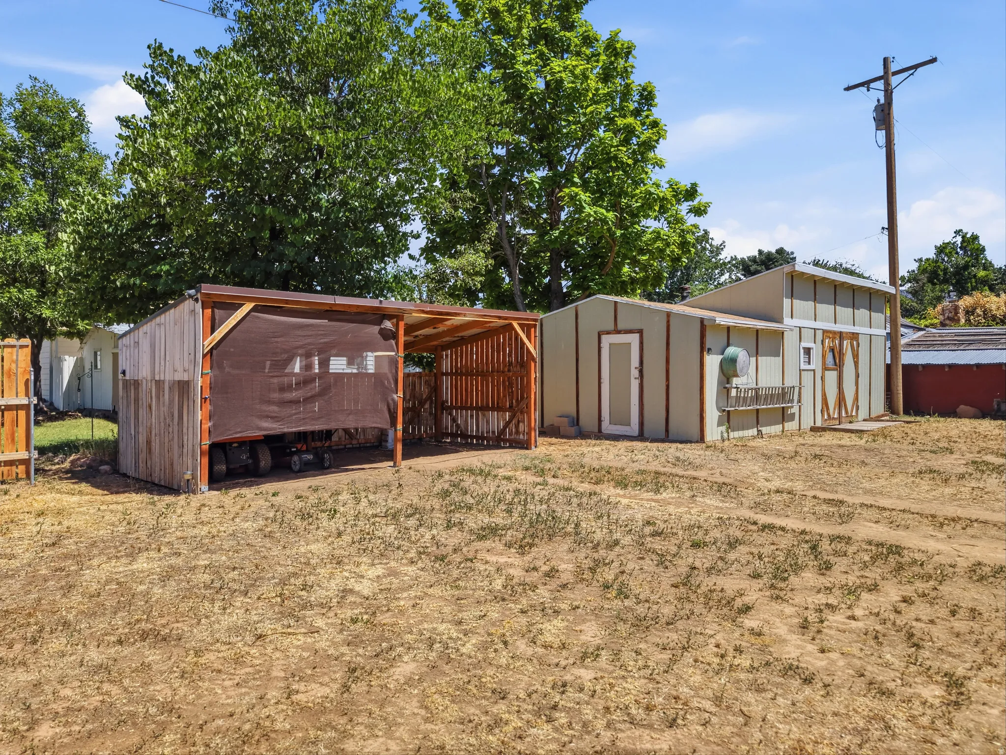 Expansive outdoor space featuring a detached storage shed with double barn doors, a single entry door, and a built-in window planter box