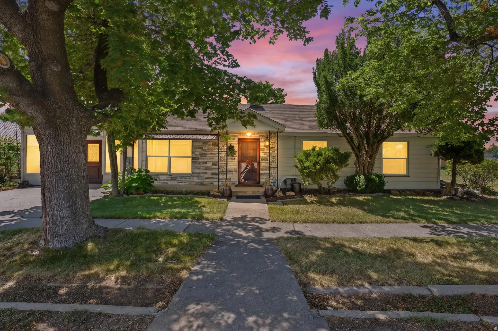 Front facade featuring stone accents, a covered porch, and a sidewalk leading to the entryway