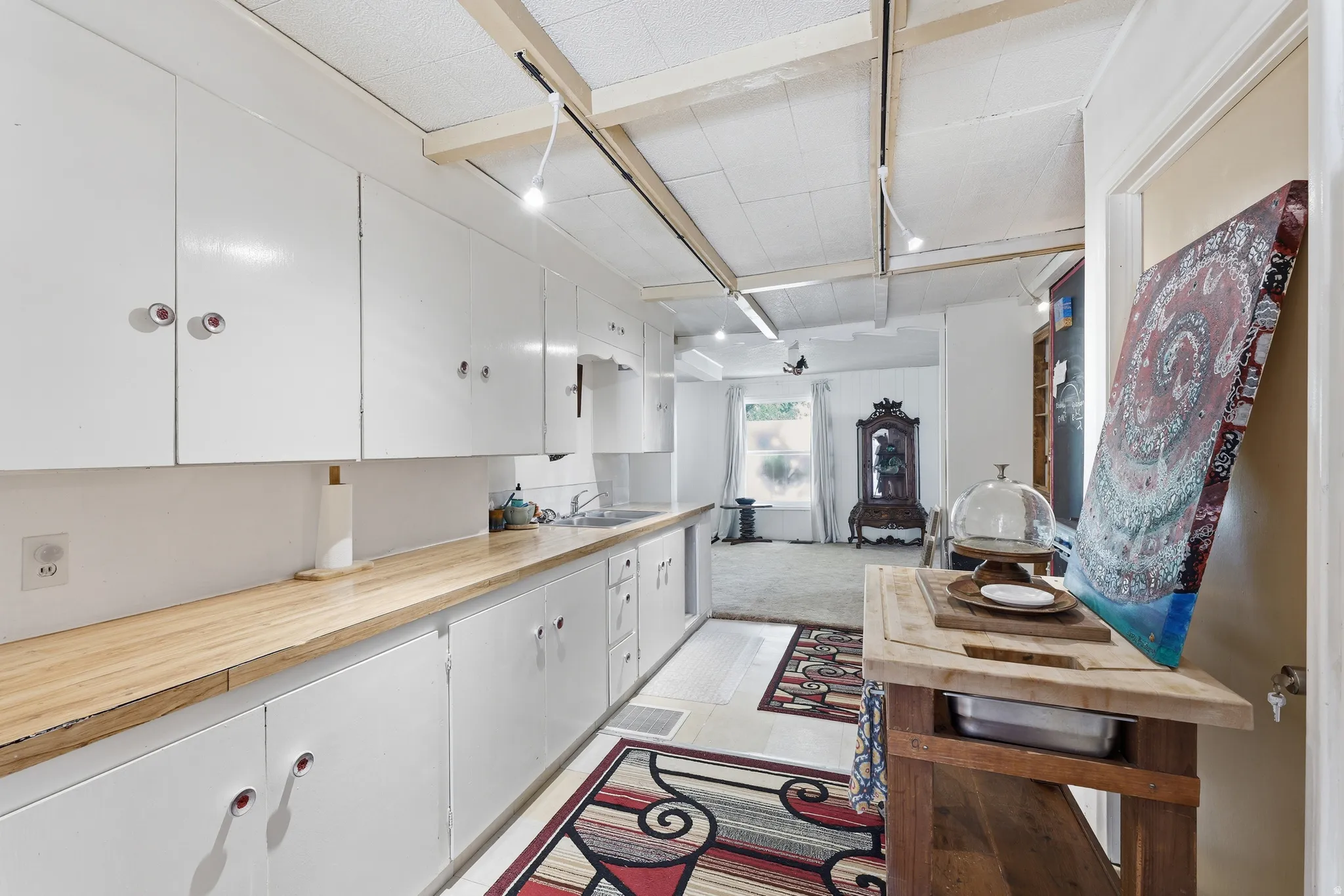 Galley-style kitchen featuring abundant white cabinetry, wood-finish countertops, and track lighting