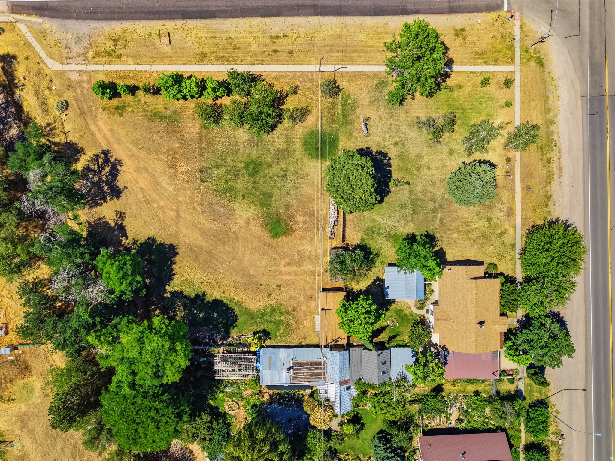 Expansive lot featuring a primary residence with a brown shingle roof, accompanied by a secondary structure with a metal roof