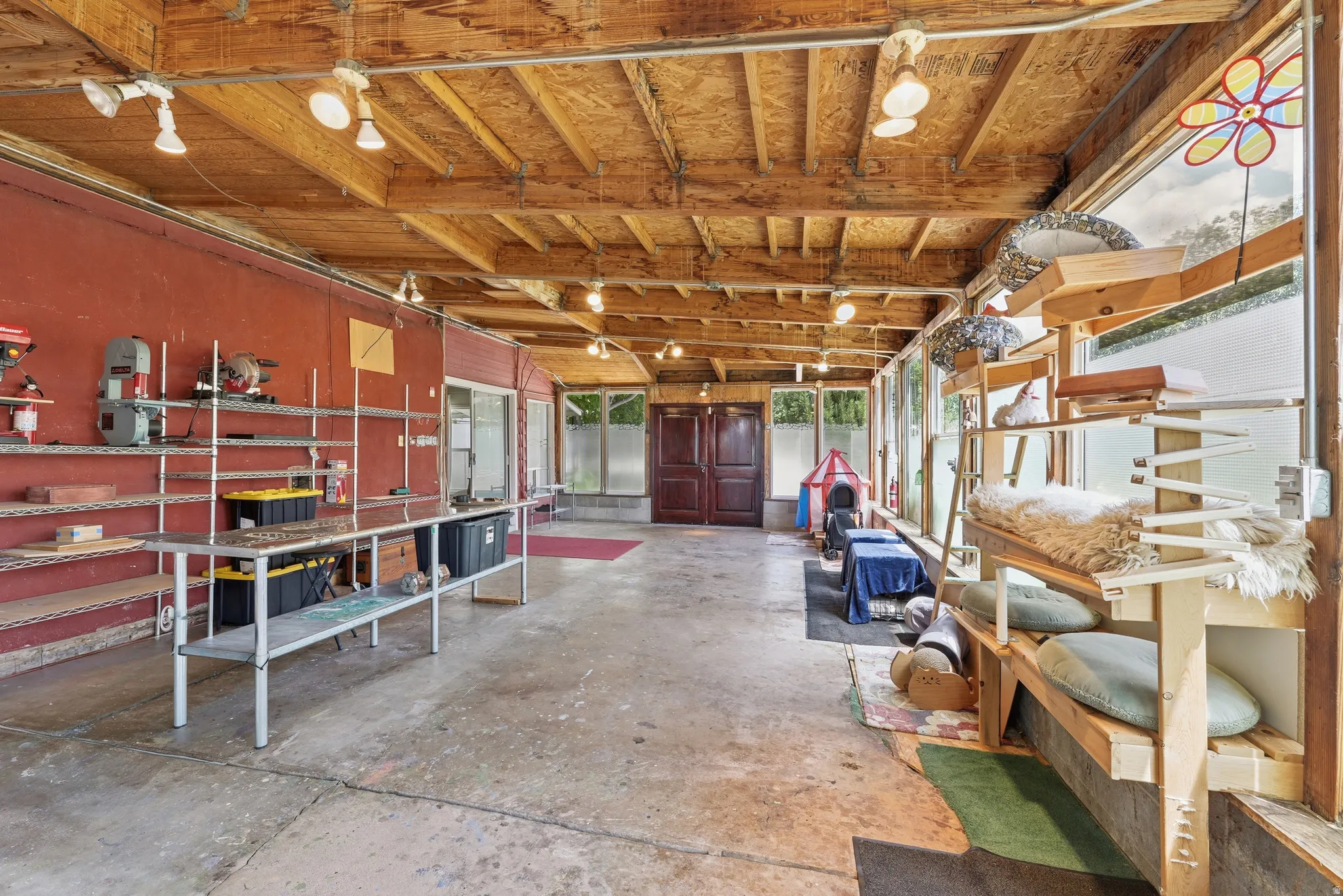 Versatile enclosed space featuring a high wood-finish ceiling with exposed beams, concrete flooring, and multiple windows
