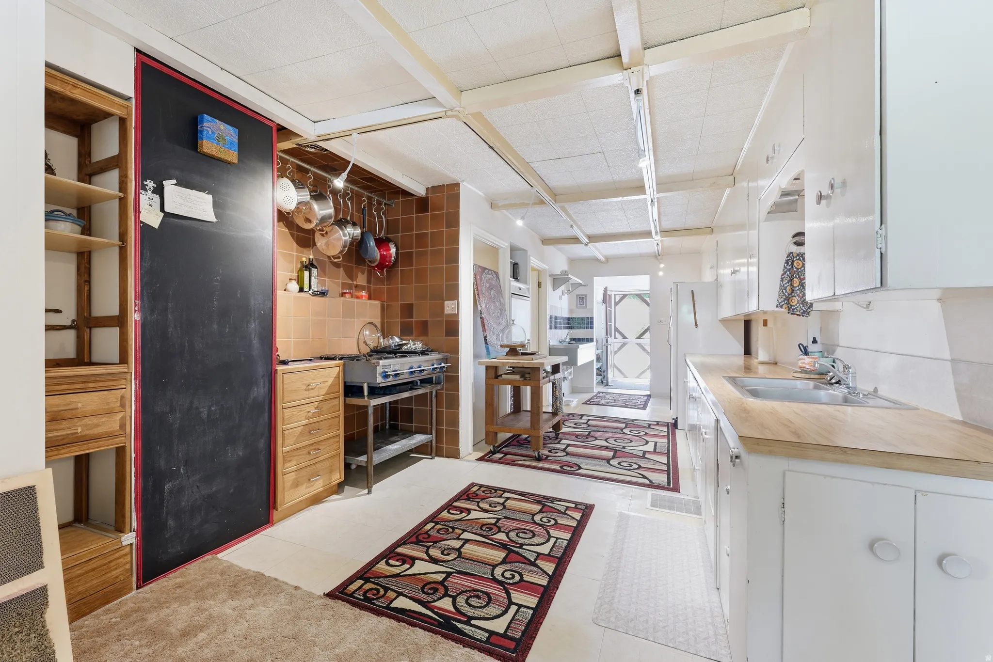 Kitchen featuring white cabinetry, wood-finish countertops, and a stainless steel sink with a chrome faucet