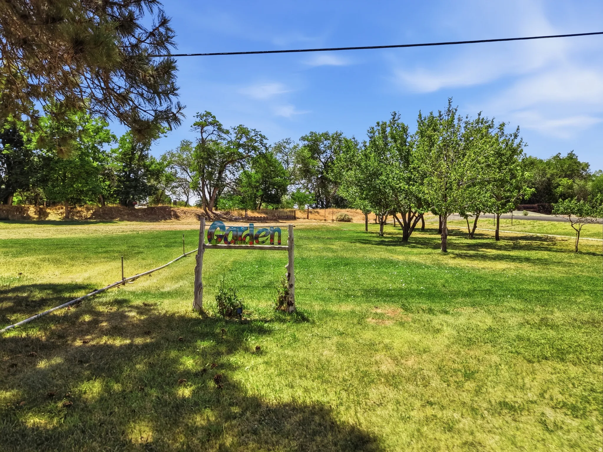 Expansive green lawn area featuring a decorative garden sign and established trees
