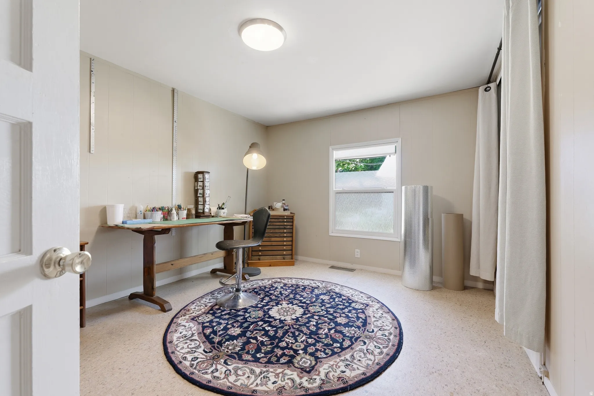 Neutral-toned room featuring a single window, overhead flush-mount lighting, and durable light-colored flooring