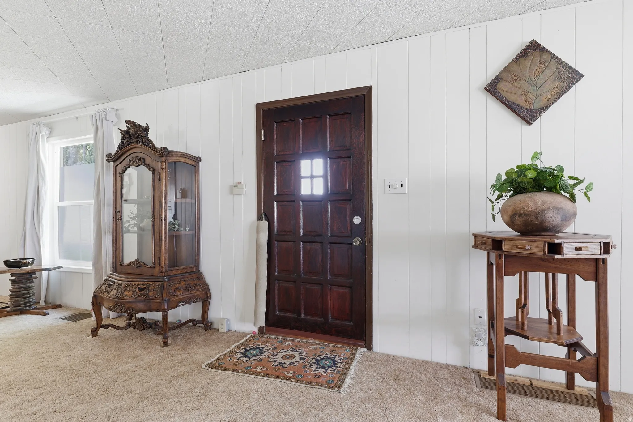 Paneled front door with a window lite, set against white vertical paneling