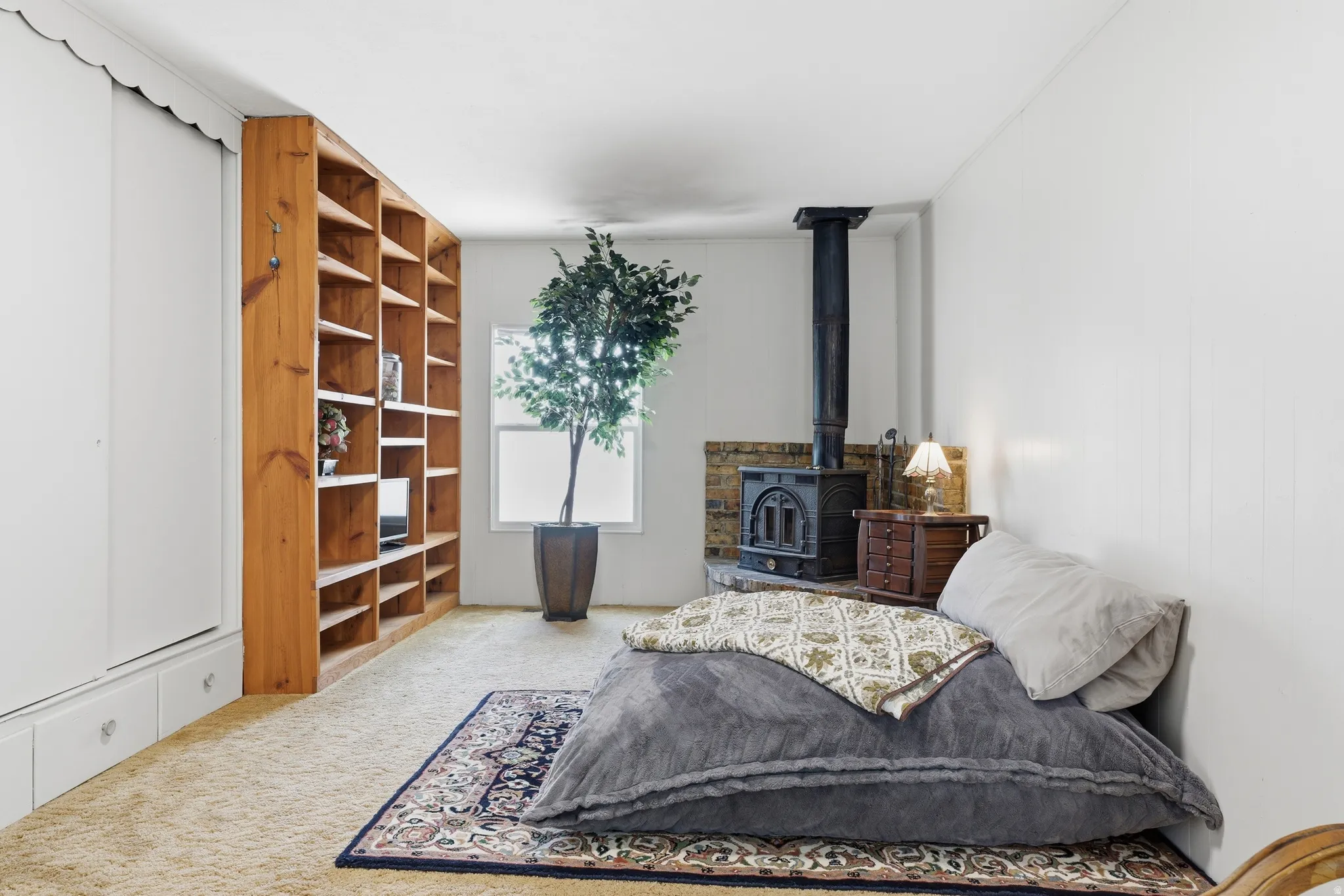 Room featuring a built-in wood-burning stove with a brick hearth, wall-to-wall carpeting, and a large window