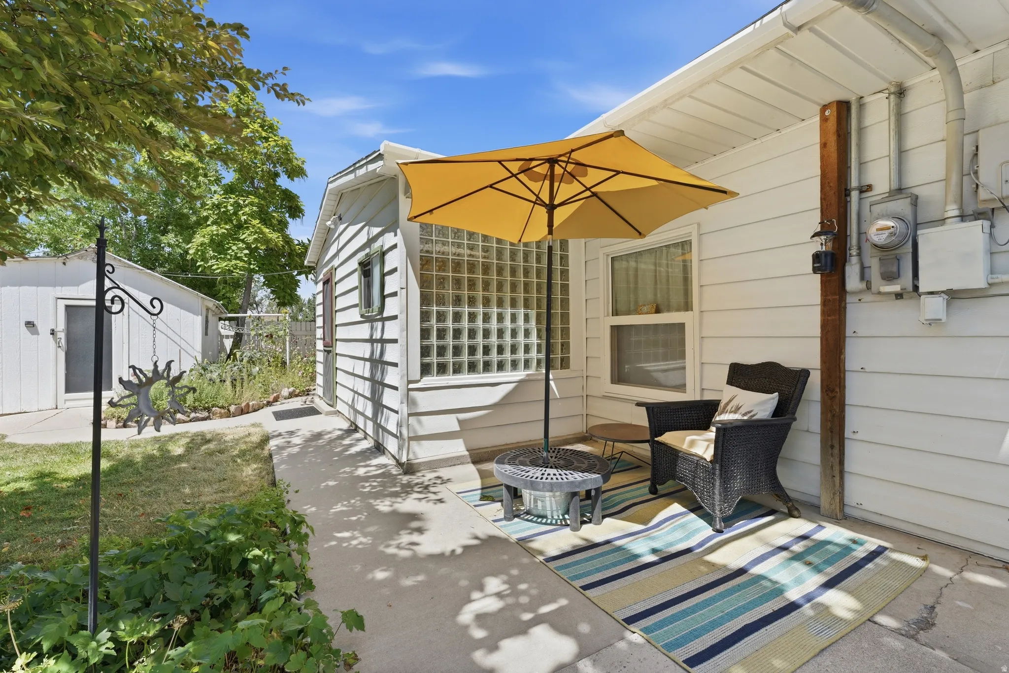 Side patio with concrete flooring, white siding, and glass block window