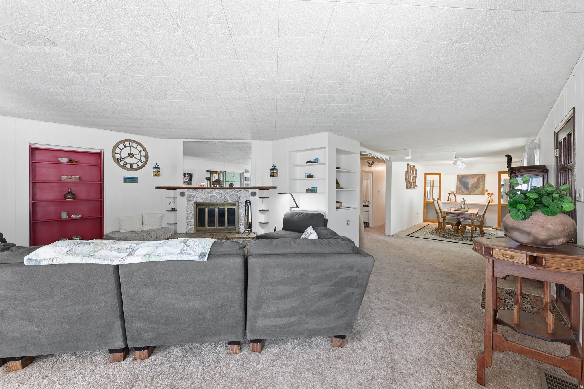Carpeted living area featuring a central fireplace with a tiled surround, a wood mantel, and built-in shelving