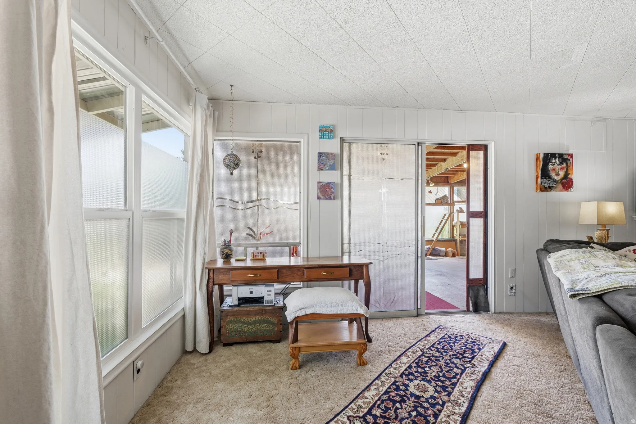 Interior room featuring multiple windows with frosted privacy film, light-toned wall paneling, and a neutral carpeted floor