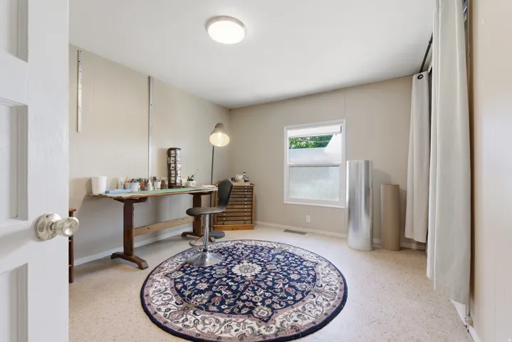 Neutral-toned room featuring a single window, overhead flush-mount lighting, and durable light-colored flooring