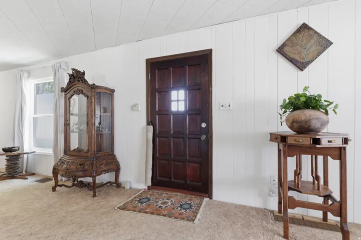 Paneled front door with a window lite, set against white vertical paneling