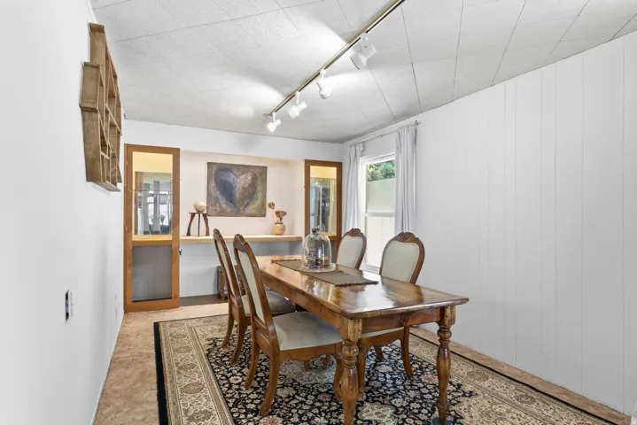 Dining area featuring a wood-finish table, recessed display niches with a wood shelf, and track lighting