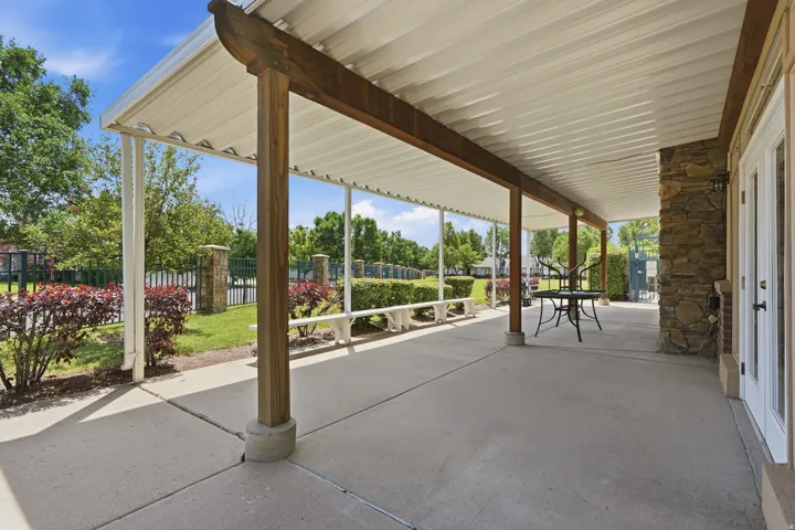Expansive covered patio featuring a concrete slab, stone veneer column, and multiple white support columns