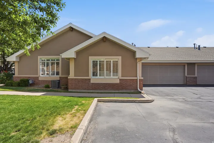 Exterior featuring stucco siding, brick detailing, and multiple garage doors