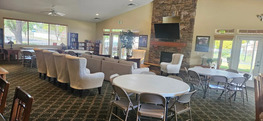 Spacious common area featuring vaulted ceilings, a stone-clad fireplace, large windows, and multiple seating arrangements