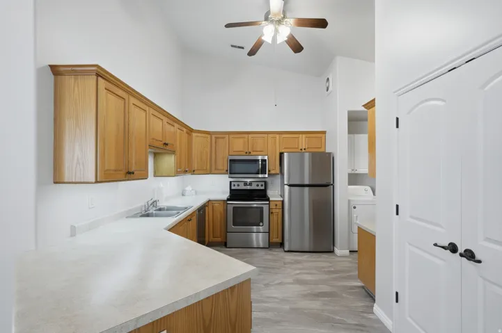 Kitchen featuring light wood cabinetry, light-toned countertops, and stainless steel appliances