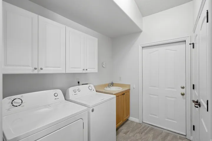 Dedicated laundry area featuring a utility sink with a light wood-finish vanity and beige countertop