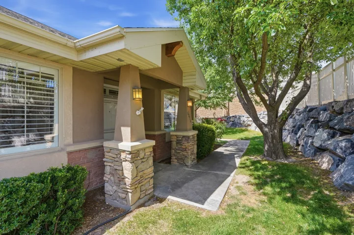 Welcoming front entry featuring stone-clad pillars, a stucco exterior, and wall-mounted sconces