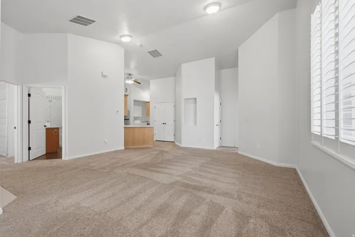 Carpeted living area featuring high ceilings, recessed architectural details, and window treatments