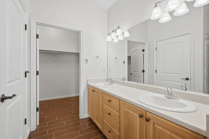 Dual vanity featuring light wood cabinetry and integrated sinks