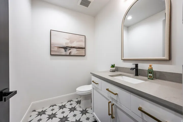 Contemporary vanity featuring a rectangular undermount sink, a matte black faucet, and brass hardware