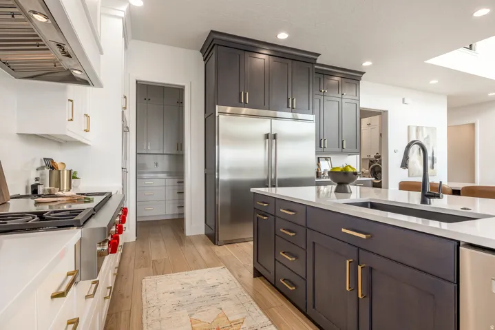 Gourmet kitchen featuring a substantial central island with an undermount sink, a stainless steel refrigerator, and wood-finish flooring
